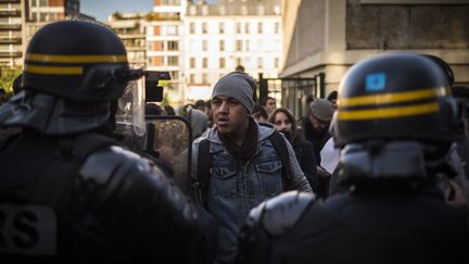 Un migrant faisant face à un cordon de policiers lors d'un "contrôle administratif" dans le campement de Stalingrad, lundi 31 octobre 2016 à Paris.&nbsp; (LIONEL BONAVENTURE / AFP)