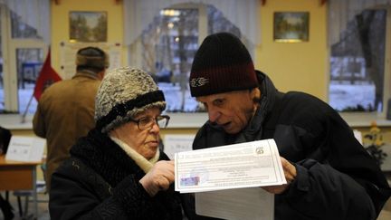 Des &eacute;lecteurs lisent les bulletins de vote le 4 d&eacute;cembre 2011 dans un bureau de vote de Moscou (Russie). (KIRILL KUDRYAVTSEV / AFP)