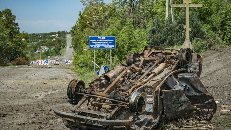 Une voiture détruite sur la route menant au village de Dolnya, dans le Donbass, dans l'est de l'Ukraine, le 2 juin 2022.&nbsp; (CELESTINO ARCE / AFP)