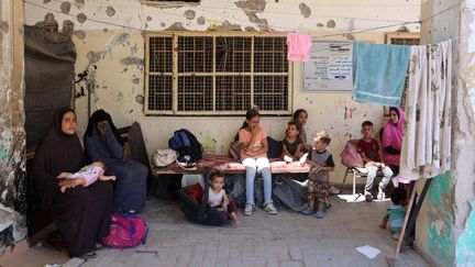 Des femmes et des enfants palestiniens sont assis à l'école al-Zahra, après qu'elle a été touchée par une frappe israélienne dans le quartier de Shujaiya (Gaza), le 8 août 2024. (OMAR AL-QATTAA / AFP)