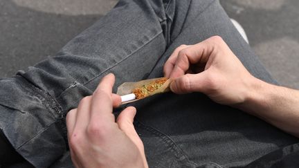 Un participant à la manifestation mondiale pour la légalisation du cannabis roulant un joint, à Paris, le 29 avril 2017. (ALAIN JOCARD / AFP)