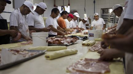 Des travailleurs préparent des roulés au jambon en vue du Nouvel An, le 30 décembre 2011, à Caracas (Venezuela). (CARLOS GARCIA RAWLINS / REUTERS)