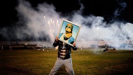 lors d’un match de football, un supporter de Mouammar Kadhafi brandit un portrait du leader libyen alors que des feux d'artifice sont tirés sur le terrain d’un stade dans la banlieue de Zaouïa (50 km à l’ouest de Tripoli). La ville est alors sous le contrôle des forces fidèles au «guide». (Moises Saman / Magnum Photos)