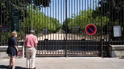 Deux personnes devant la grille fermée du jardin du Luxembourg, à Paris, le 26 avril 2020.&nbsp; (LAURE BOYER / HANS LUCAS / AFP)