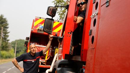 Deux sapeurs-pompiers devant leur véhicule d'intervention dans la commune de Louchats, en Gironde. (ROMAIN PERROCHEAU / AFP)