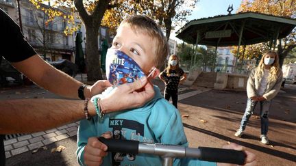 Un homme met un masque à un enfant, dans une commune du Var, le 11 novembre 2020. (PH ARNASSAN / MAXPPP)