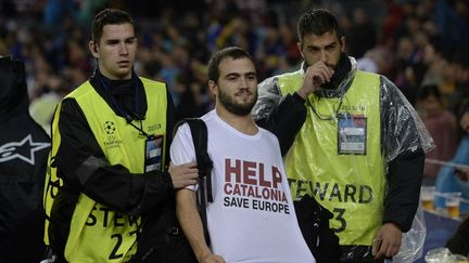 Un homme portant une tee-shirt appelant à sauver la Catalogne est escorté par le service de sécurité du Camp Nou le 18 octobre 2017 à Barcelone. (JOSEP LAGO / AFP)