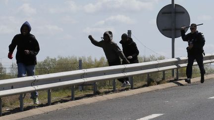 Un policier repousse des migrants aux abords du port de Calais, le 28 avril 2015. (FRANCOIS MORI / AP / SIPA)