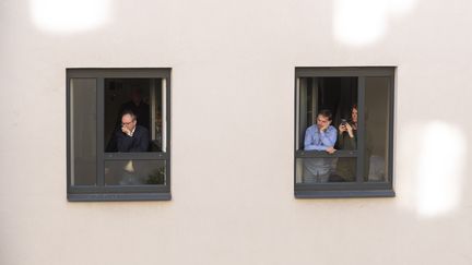 Des habitants de Vienne (Autriche) regardent, depuis leur fenêtre, un concert donné par des chanteurs&nbsp;accompagnés par un&nbsp;orchestre, lors du confinement, le 30 mai 2020. (JOE KLAMAR / AFP)