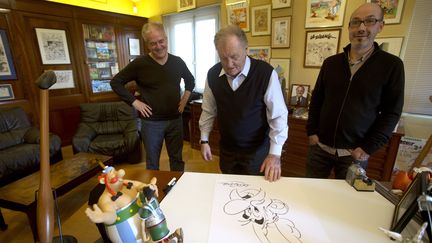 Didier Conrad, le nouveau dessinateur d'Ast&eacute;rix et Jean-Yves Ferri, le nouveau sc&eacute;nariste, entourent Albert Uderzo, cr&eacute;ateur historique de la s&eacute;rie, le 10 octobre 2013, &agrave; Neuilly-sur-Seine.&nbsp; (JOEL SAGET / AFP)