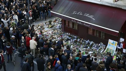 Des dizaines de Parisiens se recueillent devant le bar Le Carillon, le 15 novembre 2015, dans le 11e arrondissement de la capitale. (BENOIT TESSIER / REUTERS)