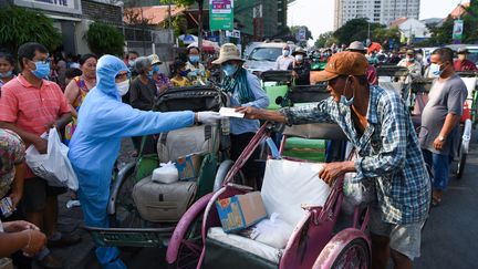 Un représentant d'une riche famille cambodgienne distribue des dons de nourriture aux conducteurs de vélo-taxis à Phnom Penh, le 30 mars 2020. (TANG CHHIN SOTHY / AFP)