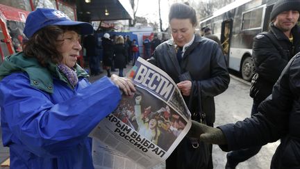 Des habitants de Simferopol, en Crim&eacute;e, d&eacute;couvrent la une des journaux au lendemain du r&eacute;f&eacute;rendum en faveur au rattachement &agrave; la Russie, lundi 17 mars 2014.&nbsp; (VASILY FEDOSENKO / REUTERS )