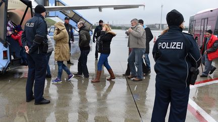 Des policiers escortent des migrants dans un avion en vue de leur expulsion, le 9 décembre 2015 à l'aéroport de Munich (Allemagne). (CHRISTOF STACHE / AFP)