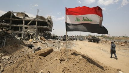 Le drapeau irakien est planté à l'entrée de la vieille ville de Mossoul, reprise par l'armée au groupe Etat islamique, le 8 juillet 2017. (AHMAD AL-RUBAYE / AFP)