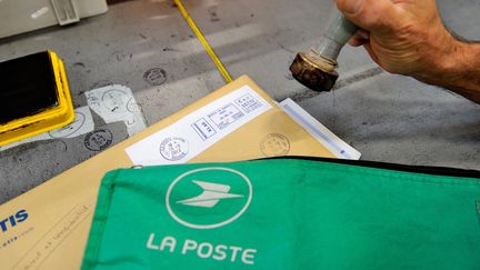 Un facteur tamponne des lettres dans un bureau de poste le 26 septembre 2013 à Lesquin (Nord). (PHILIPPE HUGUEN / AFP)