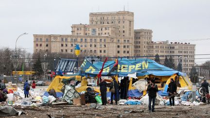 Mardi 1er mars 2022. 8h du matin. Des Ukrainiens restent près de la tente "All for Victory" de volontaires, sur la place Svobody (Liberté),&nbsp;à&nbsp;Kharkiv, au nord-est de l'Ukraine, après qu'un missile russe a frappé à l'extérieur du bâtiment du palais de l'administration régionale,&nbsp; bâtiment où se trouvait l'équipe de tournage de TF1-LCI.&nbsp; (VYACHESLAV MADIYEVSKYY / NURPHOTO VIA AFP)