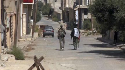 Deux soldats syriens patrouillent dans les rues de la ville d'al-Qaryatayne, dans le centre de la Syrie, le 21 octobre 2017, après sa reprise au groupe Etat islamique. (AP / SIPA)