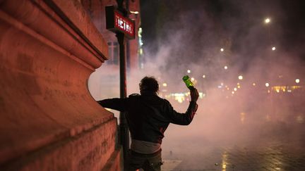 Un homme brandit une bouteille en verre, sur la place de la République, à Paris, en marge du mouvement Nuit Debout, le 23 avril 2016. (ELLIOTT VERDIER / AFP)