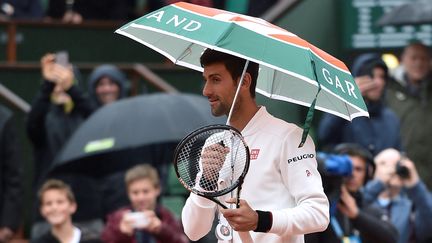 Le Serbe Novak Djokovic s'amuse de la pluie qui tombe sur Roland-Garros le 31 mai 2016 à Paris. (ERIC FEFERBERG / AFP)