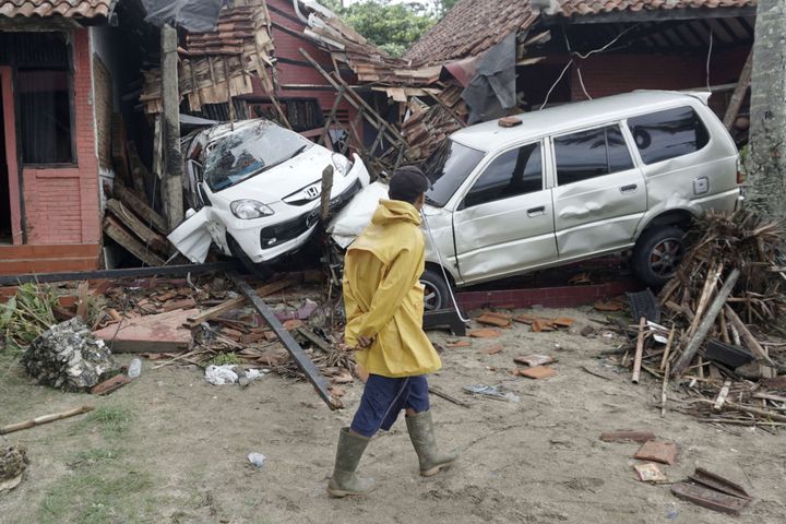 Un homme observe des voitures déplacées par un tsunami et projetées dans des habitations, à Carita (Indonésie), le 23 décembre 2018. (DIAN TRIYULI HANDOKO / AP / SIPA)