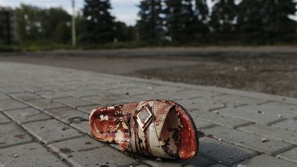 Une sandale couverte de sang dans une rue de&nbsp;Makiivka (Ukraine) apr&egrave;s un bombardement, le 19 ao&ucirc;t 2014. (MAXIM SHEMETOV / REUTERS)