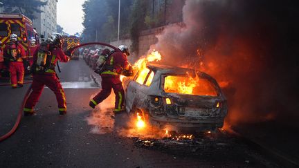 Des pompiers tentent d'éteindre une voiture en feu à Nanterre, à l'ouest de Paris, le 27 juin 2023. (ZAKARIA ABDELKAFI / AFP)