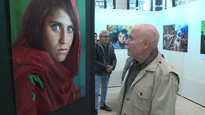 Le photographe Steve McCurry devant le portrait de la jeune Afghane du camp de réfugiés en 1985 (France 3 Champagne-Ardenne)