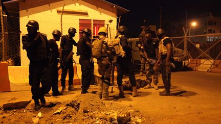 Des soldats maliens autour du corps de l'un des assaillants de l'hôtel de la mission militaire de l'Union européenne, le 21 mars 2016 à Bamako (Mali). (BABA AHMED / SIPA / AP)