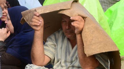 Un p&eacute;lerin se refugie sous un carton pour s'abriter de la pluie, &agrave; la Mecque, le 5 octobre 2014. (DILEK MERMER / ANADOLU AGENCY/AFP PHOTO)