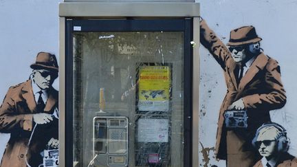 L'oeuvre de Banksy apparue à Cheltenham le 13 avril 2014, montrant des agents gouvernementaux espionnant une cabine téléphonique.
 (Jules Annan/Photoshop/MAXPPP )