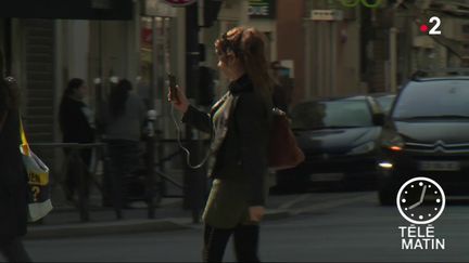 Une femme regardant son smarphone en traversant. (France 2)