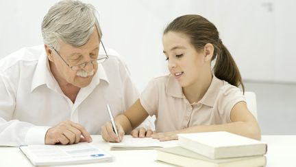 Un sénior surveille les devoirs d'une fille. (ERIC AUDRAS / MAXPPP)