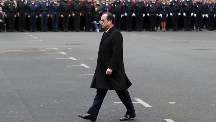 Le président François Hollande passe les troupes en revue, lors de l'hommage rendu à&nbsp;Clarissa Jean-Philippe, Franck Brinsolaro et Ahmed Merabet, le 13 janvier 2015, à la préfecture de police de Paris. (PATRICK KOVARIK / AFP)