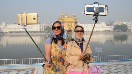 Deux touristes se prennent en photo devant un temple à Amritsar (Inde), le 14 novembre 2016. (NARINDER NANU / AFP)