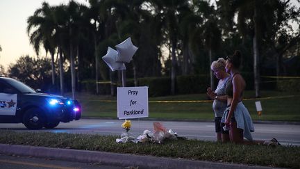 Deux Américaines prient pour les 17 morts de la fusillade dans le lycée de&nbsp;Marjory Stoneman Douglas de Parkland, en Floride (Etats-Unis), le 17 février 2018. (AFP)