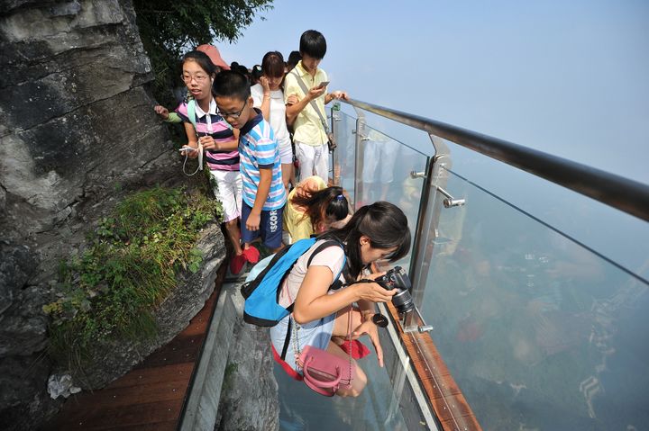 Des visiteurs parcourent un sentier transparent dans le parc forestier national de Zhangjiajie (Chine), lundi 1er août 2016. (VCG / VISUAL CHINA GROUP / AFP)