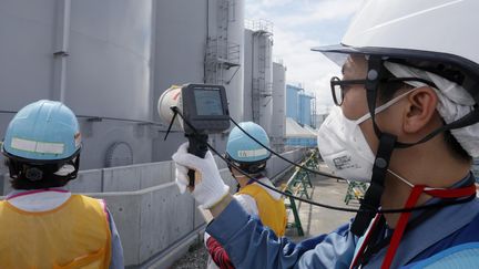 Un employé de TEPCO mesure le niveau de radiation près de la centrale de Fukushima. (KIMIMASA MAYAMA / POOL)