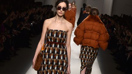 A l'exception de Prada, un certain minimalisme plane sur les podiums avec des total look blanc ou noir, dynamités ici et là par des pièces d'un rouge vif, comme chez Fendi, où rigueur et géométries servent de fil conducteur. Karl Lagerfeld signe une fois de plus pour le fourreur romain une collection composée d'ensembles pour la plupart monochromes (blancs, noirs,rouges et brique). Le cuir est partout. Il est utilisé pour façonner une longue robe blanche, appliqué par grands carrés en maxi poches sur les flancs d'une robe, ou composant par pans de différentes longueurs dans des teintes contrastées (noir, réglisse, marron) des jupes à panneaux. On le retrouve dans des tabliers trapèze à larges bretelles, proposés aussi sous forme de gilets plus courts. Le propos s'adoucit sur la fin du défilé avec des robes-doudounes crème taillées dans des couettes et des robes bustier duvet rose pâle. Les mannequins sont hissées sur des boots fourrées au talon en forme de glaçon légèrement rentré sous la semelle. Elles déambulent en serrant fort leur sac à main, d'où sort, bec en avant, un strelitzia, fleur plus connue sous le nom d'oiseau de paradis.
 (GIUSEPPE CACACE / AFP)