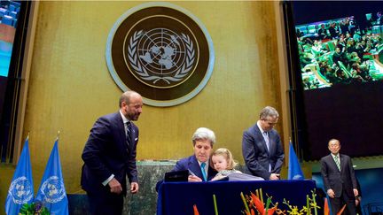 &nbsp; (Le secrétaire d'Etat américain John Kerry, signant l'accord de la COP 21 avec sa petite-fille Isabelle, deux ans, dans les bras  © UPI MAXPPP)