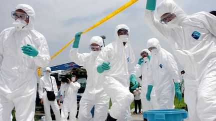 Des équipes médicales japonaises inspectent une ferme de poulets à touchée par la grippe aviaire en 2005.&nbsp; (STR / POOL)