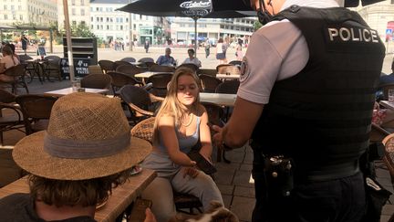 Un policier contrôle le pass sanitaire d'une cliente d'un bar assise en terrasse, le 12 août 2021 (illustration). (LÉA GIRAUDEAU / RADIO FRANCE)