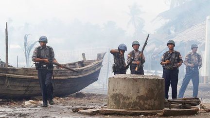 protègent des pompiers qui luttent contre un incendie.

En 1978, 200.000 Rohingyas fuient la junte birmane pro-bouddhiste en émigrant en masse vers le Bangladesh. Les militaires, sous le prétexte de lutter contre l’immigration clandestine, commettent viols, arrestations et exécutions.

Les villages et les mosquées sont pillés et incendiés. L’année suivante, beaucoup de ceux qui avaient fui sont rapatriés par le Haut-Commissariat des Nations-Unies pour les réfugiés (HCR). (REUTERS/Soe Zeya Tun)