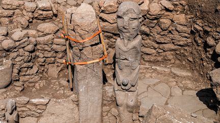 La statue de l'homme de pierre assis, empoignant son sexe à deux mains, un vautour à ses pieds, sur le site archéologique de.Karahantepe en Turquie le 23 octobre 2023 (OZAN KOSE / AFP)