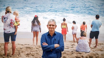 Le photographe Martin Parr pose devant l'un de ses clichés, lors de la présentation de l'exposition "Only Human" à Londres, le 6 mars 2019 (TOLGA AKMEN / AFP)