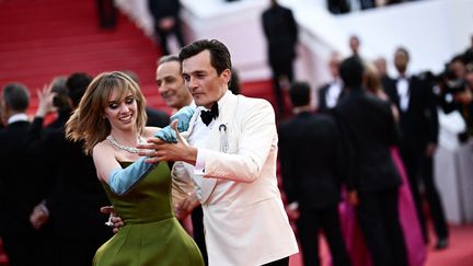 Rupert Friend, vu notamment dans la série "Homeland" fait danser Maya Hawke, révélée par la série à succès "Stranger Things", sur le tapis rouge. Les deux acteurs sont à l'affiche de "Asteroid City", le dernier film de Wes Anderson. (LOIC VENANCE / AFP)