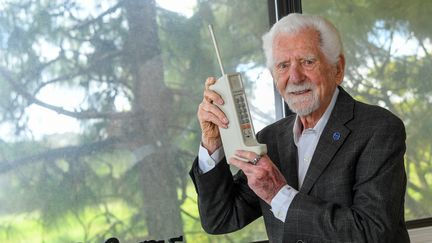 L'ingénieur Martin Cooper pose avec une copie du téléphone avec lequel il a réalisé le tout premier appel depuis un portable en 1973, à Del Mar (Californie), le 3 avril 2023. (VALERIE MACON / AFP)