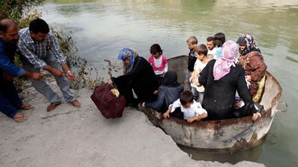 Une famille syrienne arrive en Turquie après avoir traversé le fleuve Oronte dans un réservoir d'eau, à la frontière turco-syrienne près du village de Hacipasa dans la province de Hatay, le mercredi 10 Octobre 2012. (REUTERS/Osman Orsal)