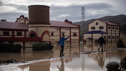 Des personnes marchent dans une rue inondée, le 29 octobre 2024 à Malaga (Espagne). (JORGE GUERRERO / AFP)