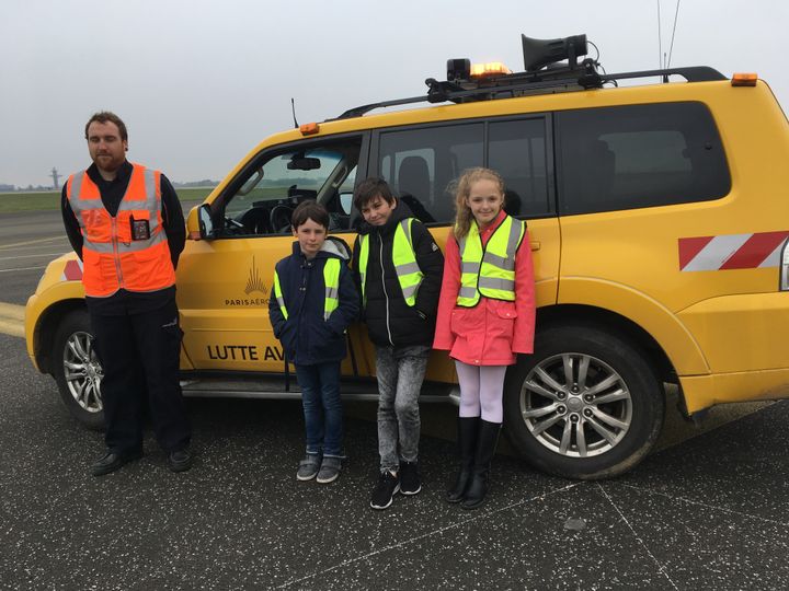 Jonathan explique son métier d'effaroucheur à Tom, Clarence et Norah sur les pistes de l'aéroport Roissy Charles-de-Gaulle. (INGRID POHU / RADIO FRANCE)